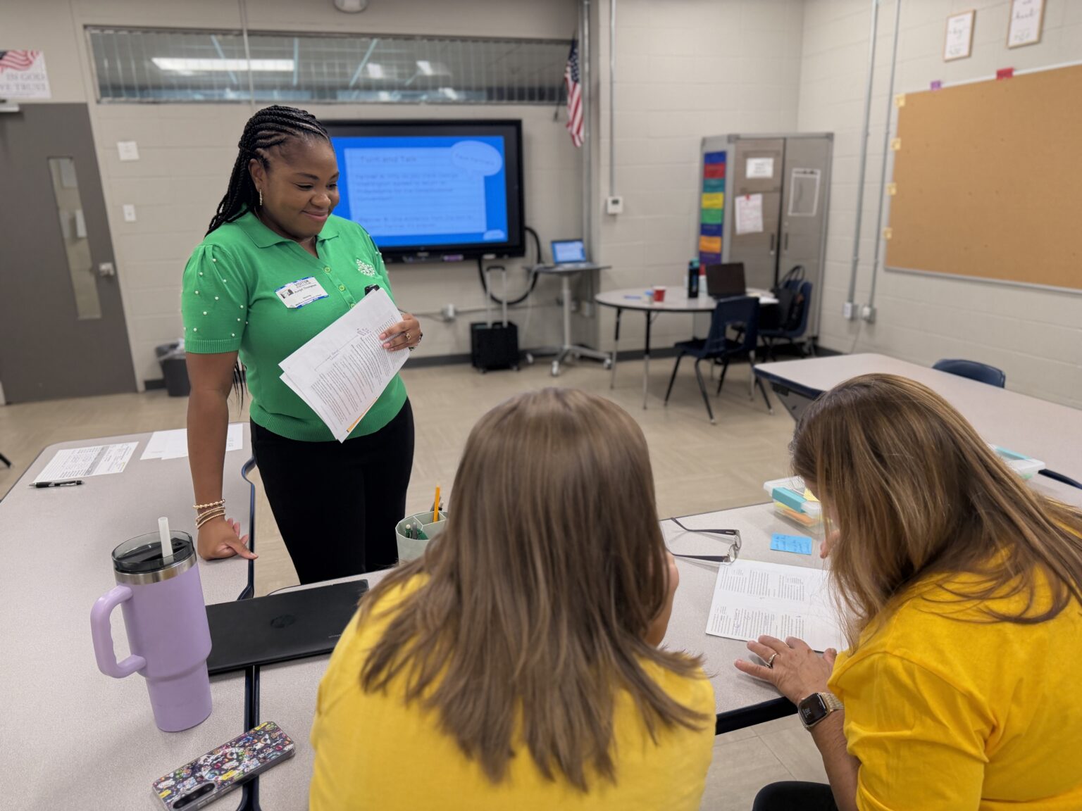 Edu20/20 team member supports two educators as they review training materials together during a professional learning session.